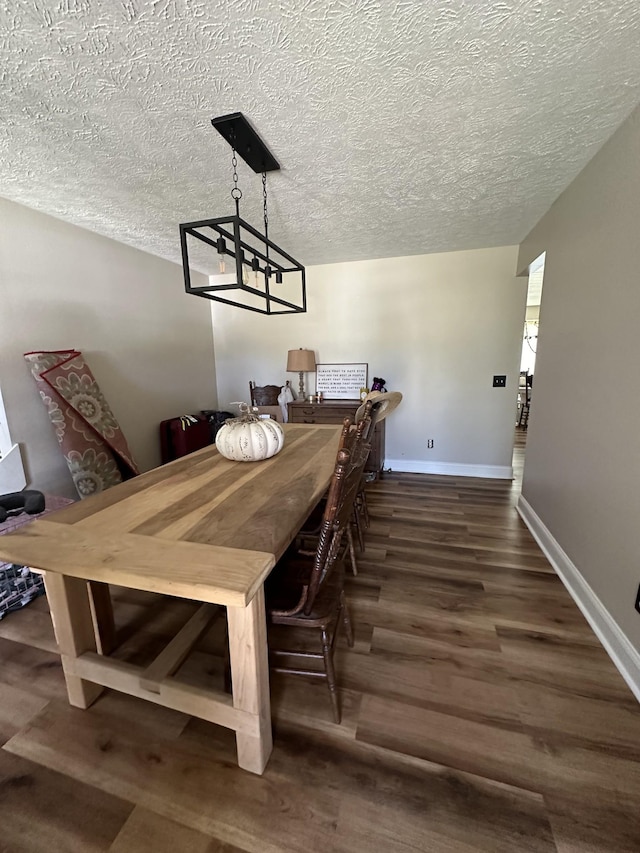 dining room with a notable chandelier, dark wood-type flooring, and a textured ceiling