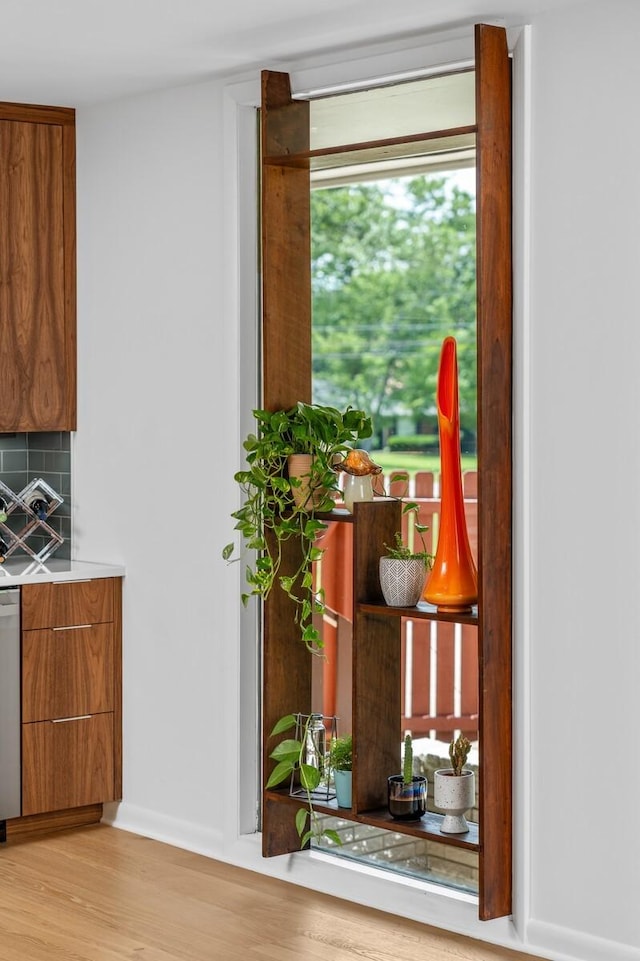 interior space featuring stainless steel dishwasher, backsplash, and light hardwood / wood-style flooring