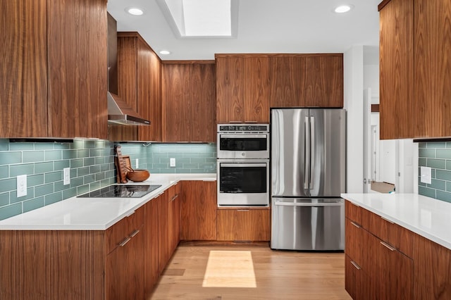 kitchen with tasteful backsplash, stainless steel appliances, ventilation hood, and light hardwood / wood-style flooring