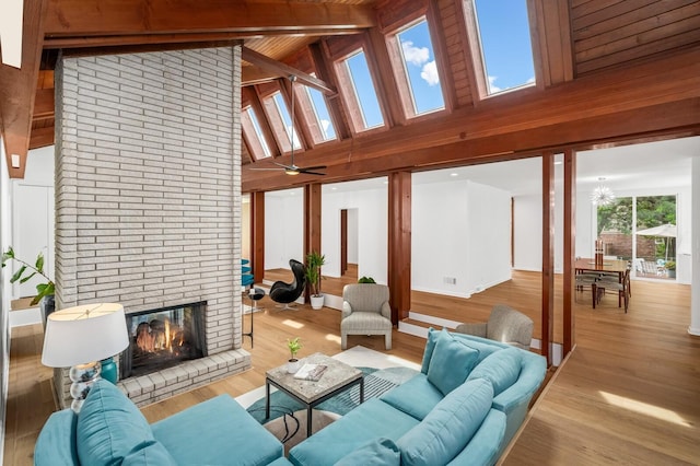 living room with beamed ceiling, a fireplace, light hardwood / wood-style floors, and high vaulted ceiling