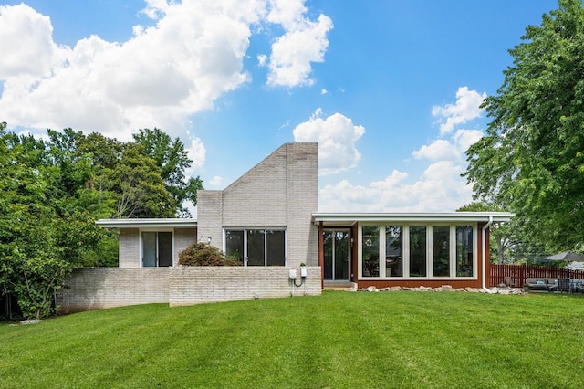 rear view of property with a yard and a sunroom