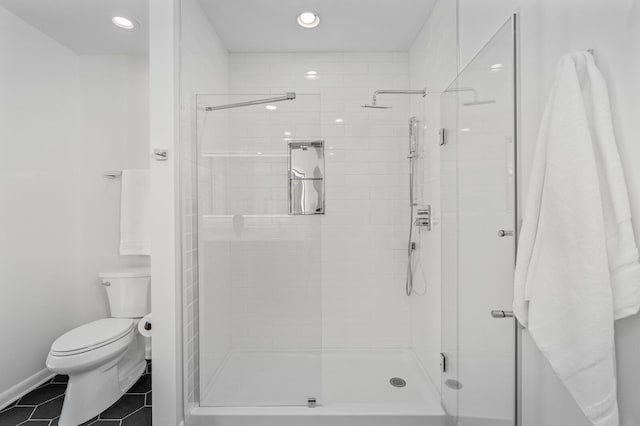 bathroom with tile patterned floors, toilet, and a shower with door