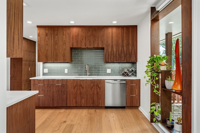 kitchen featuring backsplash, stainless steel dishwasher, sink, and light wood-type flooring