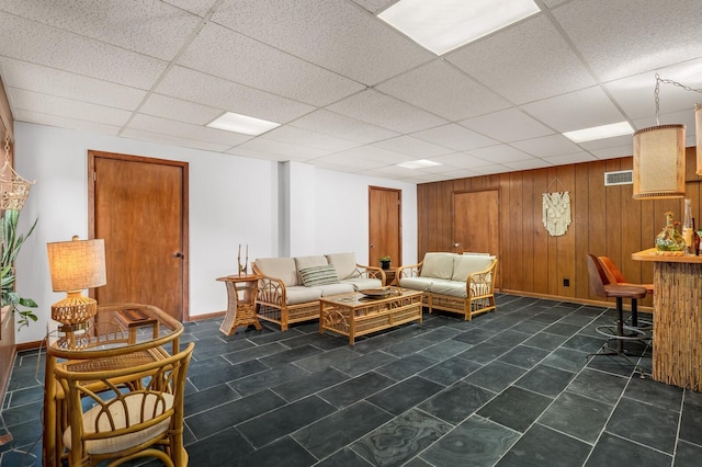 living room with a drop ceiling and wooden walls