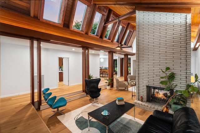 living room featuring beamed ceiling, a fireplace, light hardwood / wood-style floors, and high vaulted ceiling