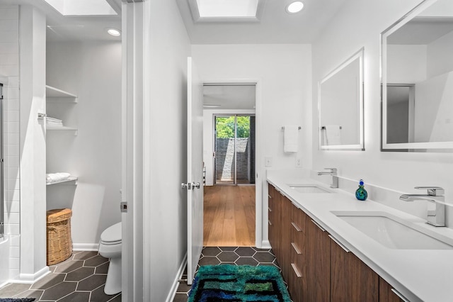 bathroom featuring tile patterned floors, toilet, a shower, a skylight, and vanity