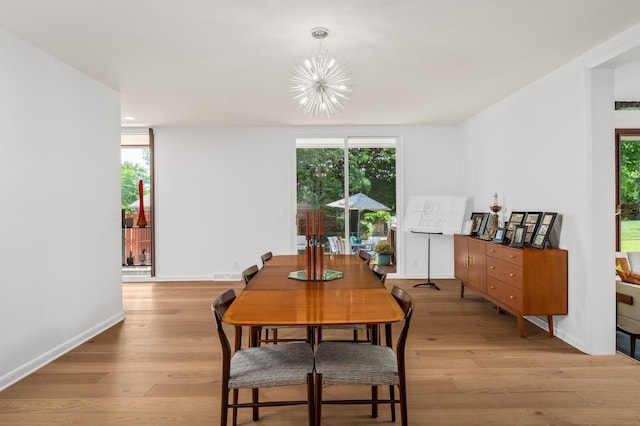 dining room featuring a healthy amount of sunlight, light hardwood / wood-style floors, and a notable chandelier