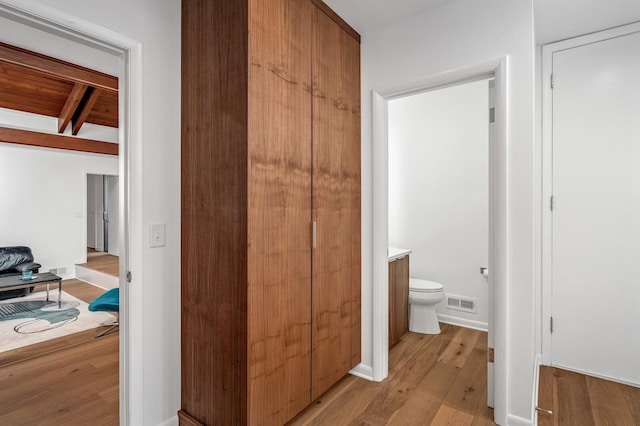 bathroom with hardwood / wood-style flooring, vanity, toilet, and beamed ceiling