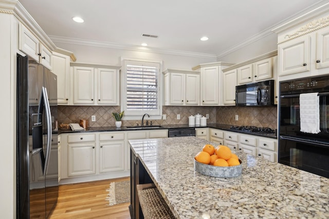 kitchen with sink, dark stone countertops, backsplash, black appliances, and crown molding