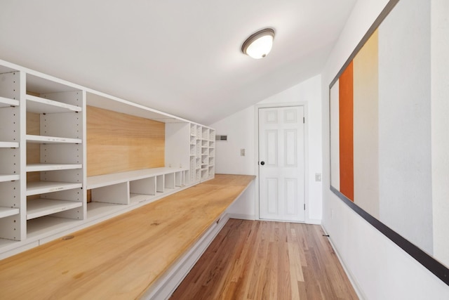 hallway with lofted ceiling and hardwood / wood-style floors