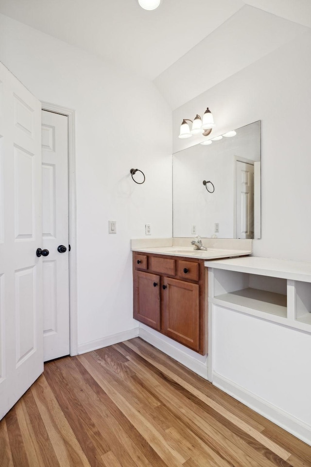 bathroom featuring lofted ceiling, wood-type flooring, and vanity