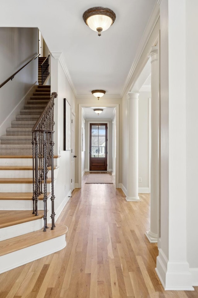 interior space featuring crown molding, wood-type flooring, and ornate columns