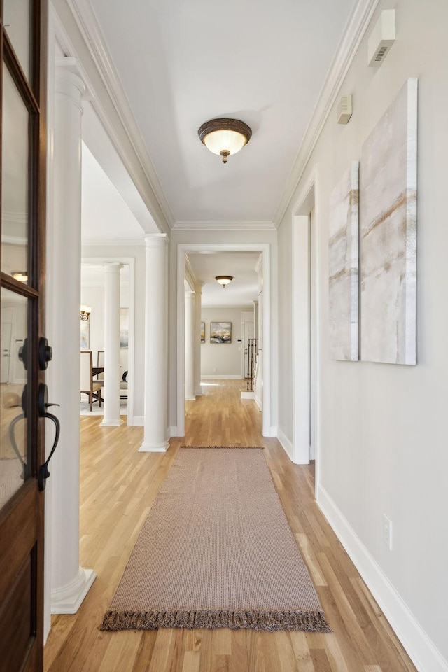 corridor featuring ornamental molding, decorative columns, and light hardwood / wood-style flooring