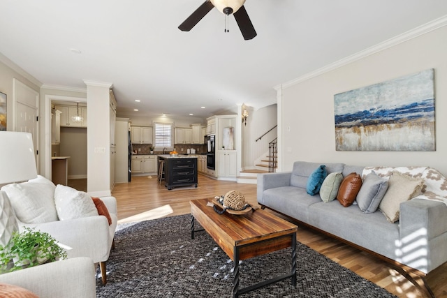 living room featuring ceiling fan, ornamental molding, and light hardwood / wood-style flooring