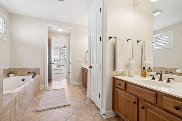 bathroom featuring a relaxing tiled tub, vanity, and tile patterned flooring