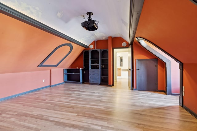 additional living space featuring vaulted ceiling and light hardwood / wood-style floors