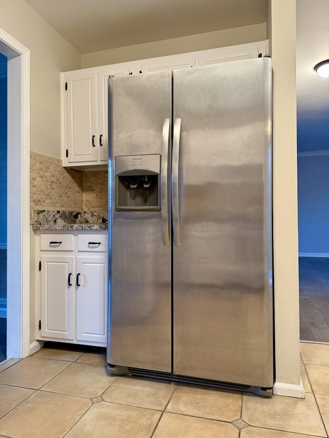 kitchen featuring light tile patterned floors, stone counters, stainless steel refrigerator with ice dispenser, tasteful backsplash, and white cabinets