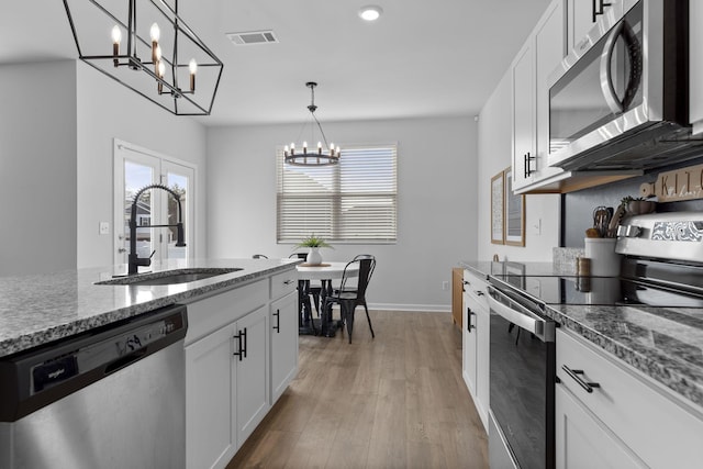 kitchen with pendant lighting, appliances with stainless steel finishes, sink, and white cabinets