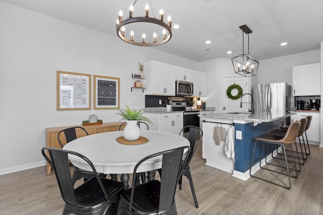 dining space featuring a chandelier, sink, and light hardwood / wood-style flooring