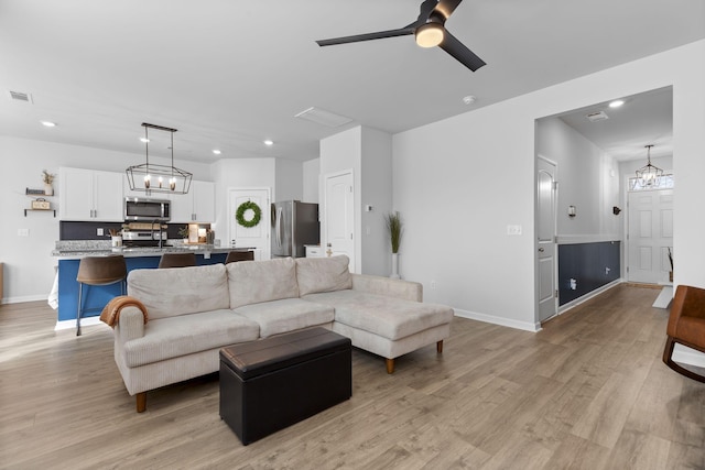 living room featuring sink, ceiling fan with notable chandelier, and light hardwood / wood-style floors