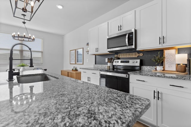 kitchen featuring sink, an inviting chandelier, appliances with stainless steel finishes, light stone countertops, and white cabinets