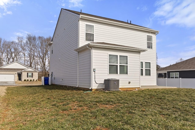 rear view of house with central AC and a lawn