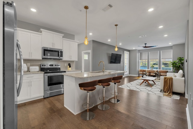 kitchen featuring stainless steel appliances, light stone countertops, pendant lighting, and white cabinets