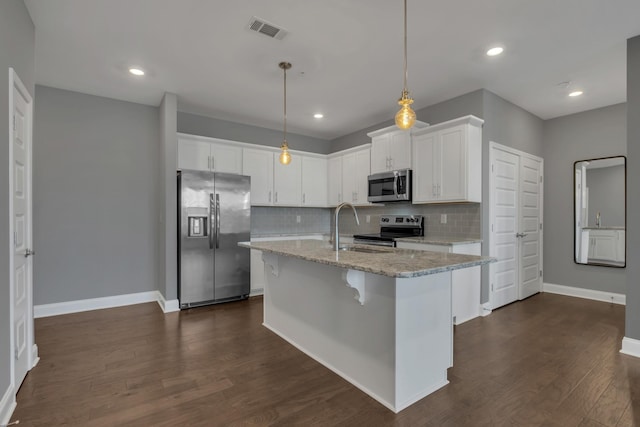 kitchen with sink, white cabinetry, decorative light fixtures, appliances with stainless steel finishes, and light stone countertops