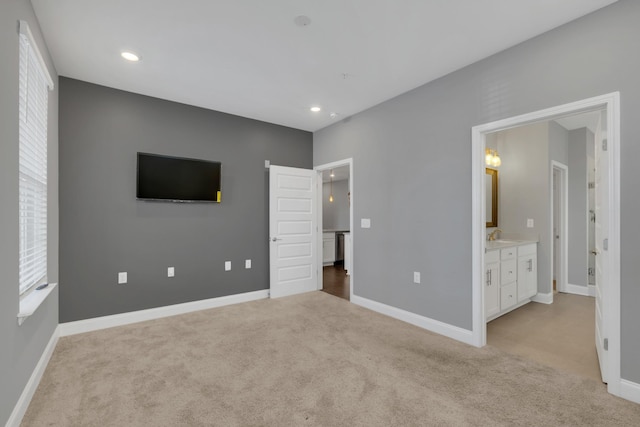 unfurnished bedroom featuring ensuite bathroom and light colored carpet