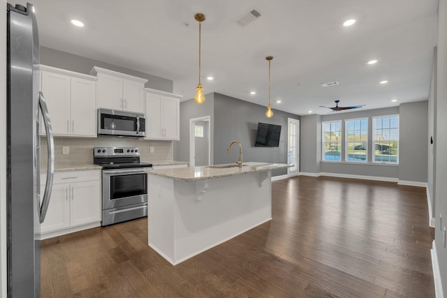 kitchen with a kitchen island with sink, white cabinetry, light stone countertops, and appliances with stainless steel finishes