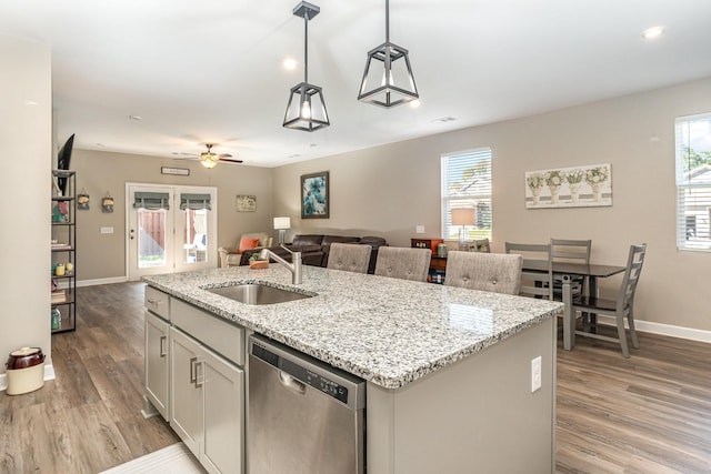 kitchen featuring sink, dishwasher, hanging light fixtures, a healthy amount of sunlight, and a center island with sink