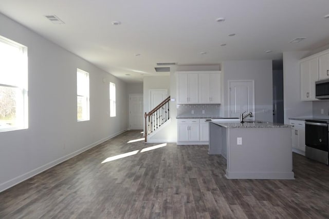 kitchen with a kitchen island with sink, white cabinetry, tasteful backsplash, and appliances with stainless steel finishes