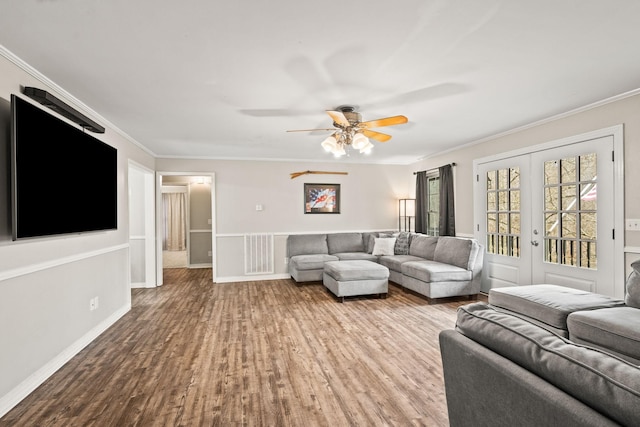 living room with crown molding, ceiling fan, french doors, and light wood-type flooring