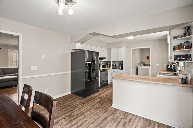 kitchen featuring sink, range with electric cooktop, white cabinets, black fridge, and kitchen peninsula