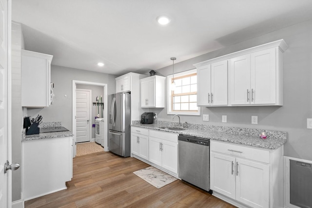 kitchen featuring sink, pendant lighting, stainless steel appliances, light hardwood / wood-style floors, and white cabinets