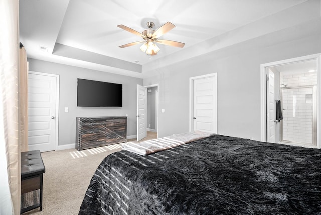 bedroom featuring carpet, connected bathroom, ceiling fan, and a tray ceiling