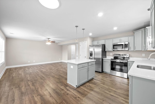 kitchen featuring a kitchen island, appliances with stainless steel finishes, decorative light fixtures, sink, and gray cabinetry