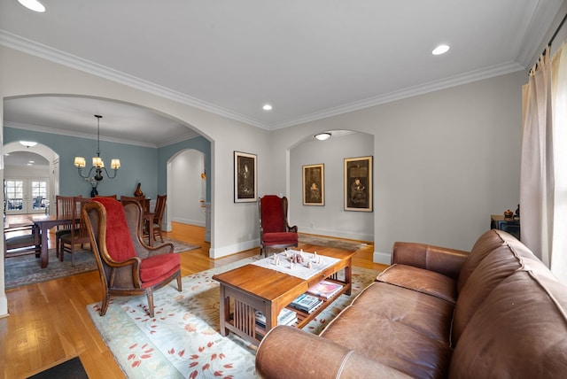 living room with ornamental molding, a notable chandelier, and light wood-type flooring