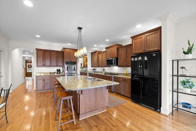 kitchen with a breakfast bar, sink, hanging light fixtures, appliances with stainless steel finishes, and a kitchen island with sink