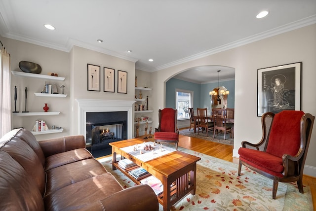 living room with an inviting chandelier, crown molding, and light wood-type flooring