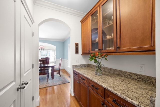 kitchen featuring ornamental molding, light stone countertops, and light wood-type flooring