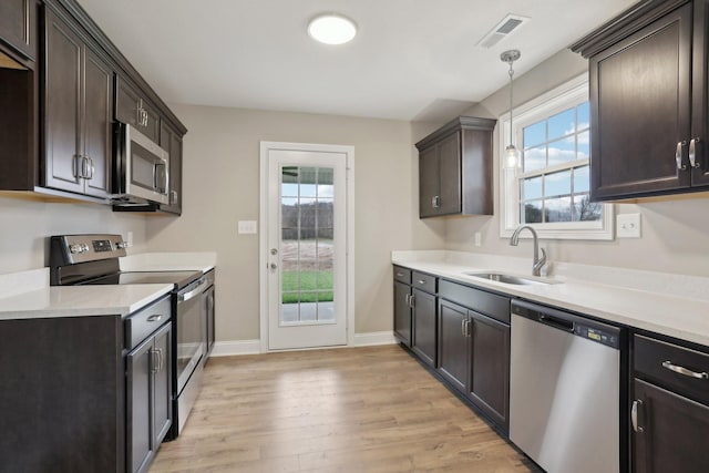 kitchen featuring stainless steel appliances, hanging light fixtures, sink, and plenty of natural light