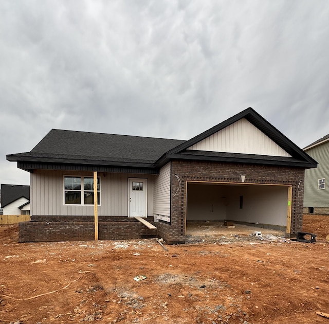 view of front of home with a shingled roof, brick siding, and an attached garage