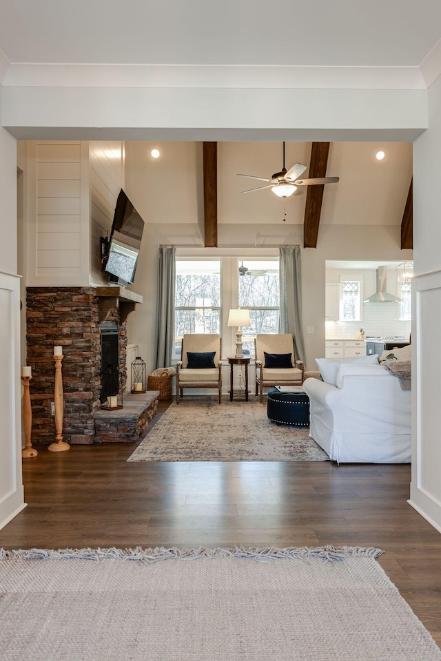 unfurnished living room featuring beam ceiling, wood-type flooring, ornamental molding, ceiling fan, and a fireplace