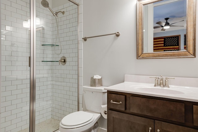 bathroom with a shower with door, vanity, ceiling fan, and toilet