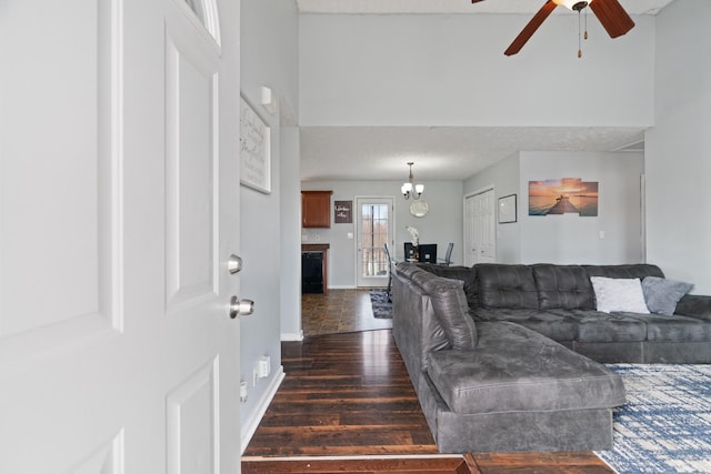 living room with dark hardwood / wood-style flooring and ceiling fan with notable chandelier