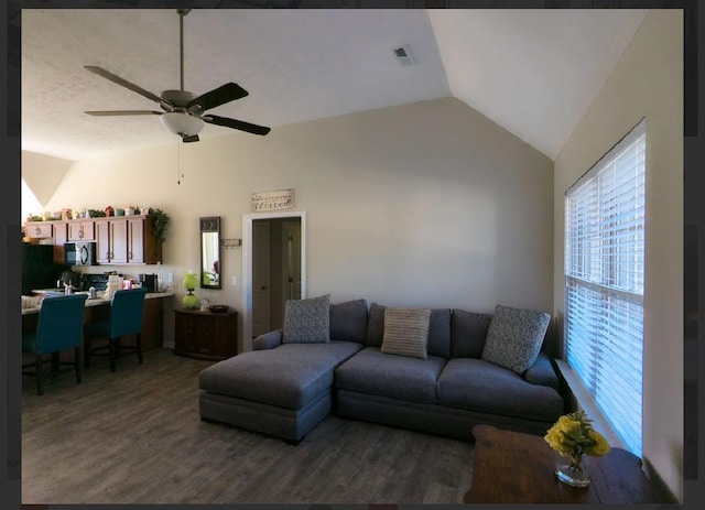 living room with ceiling fan, dark hardwood / wood-style floors, and vaulted ceiling