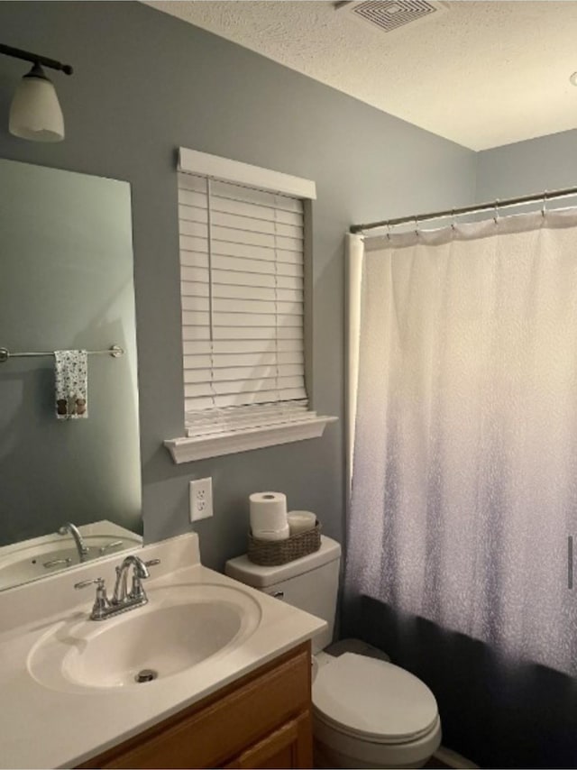 full bathroom featuring vanity, shower / bathtub combination with curtain, a textured ceiling, and toilet