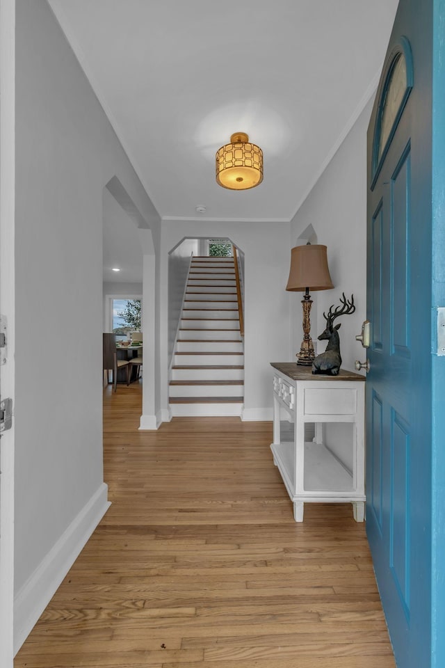 foyer entrance with crown molding and light hardwood / wood-style flooring