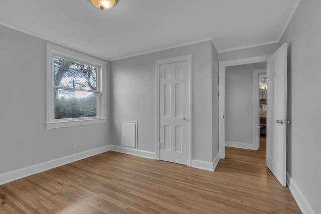 unfurnished bedroom featuring crown molding, light hardwood / wood-style floors, and a closet